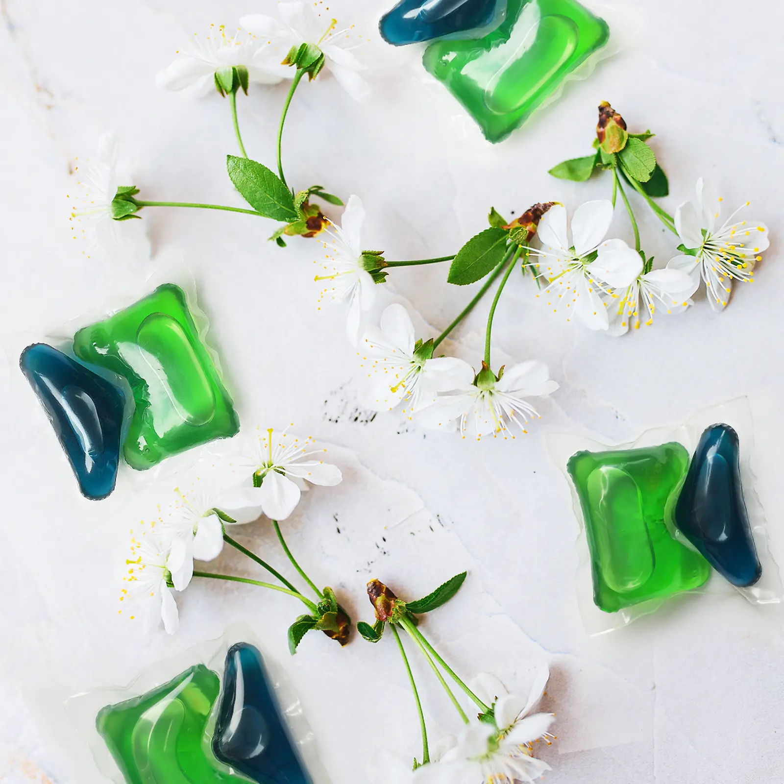 Duas pastilhas verdes e azuis de Persil da Henkel com flores de cerejeira ao redor 